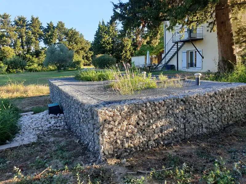 Filtre planté surélevé avec habillage en gabion pour l'assainissement d'une maison individuelle